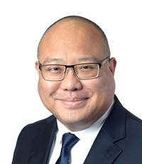 Mark Nagales's headshot: He is wearing eyeglasses, a black suit, black tie, and white collared shirt