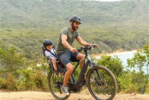 man riding bike with child in the back