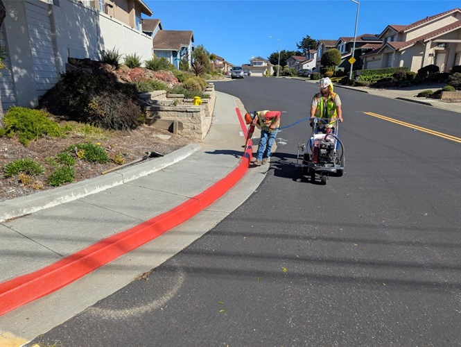 Men in yellow vests painting the curbs red for the Daylighting Law