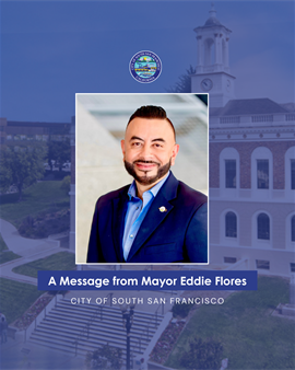 Mayor Eddie's headshot. He is wearing a blue suit with a light blue button down. His photo overlays a dark blue photo of City Hall with the words A Message from Mayor Eddie