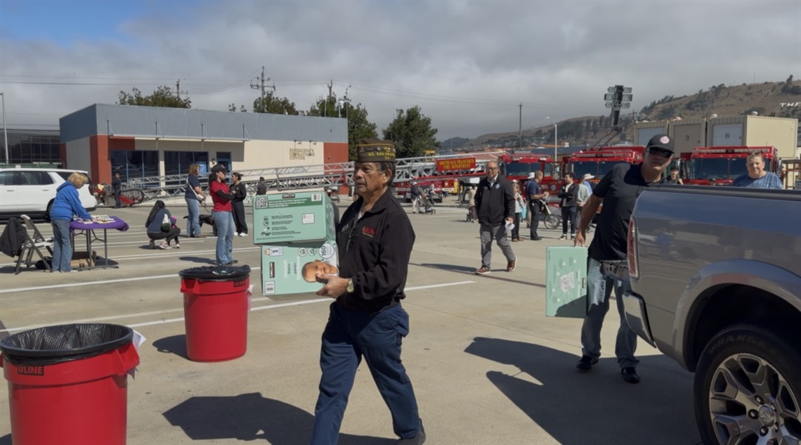 Community members carrying diapers with a fire truck in the background