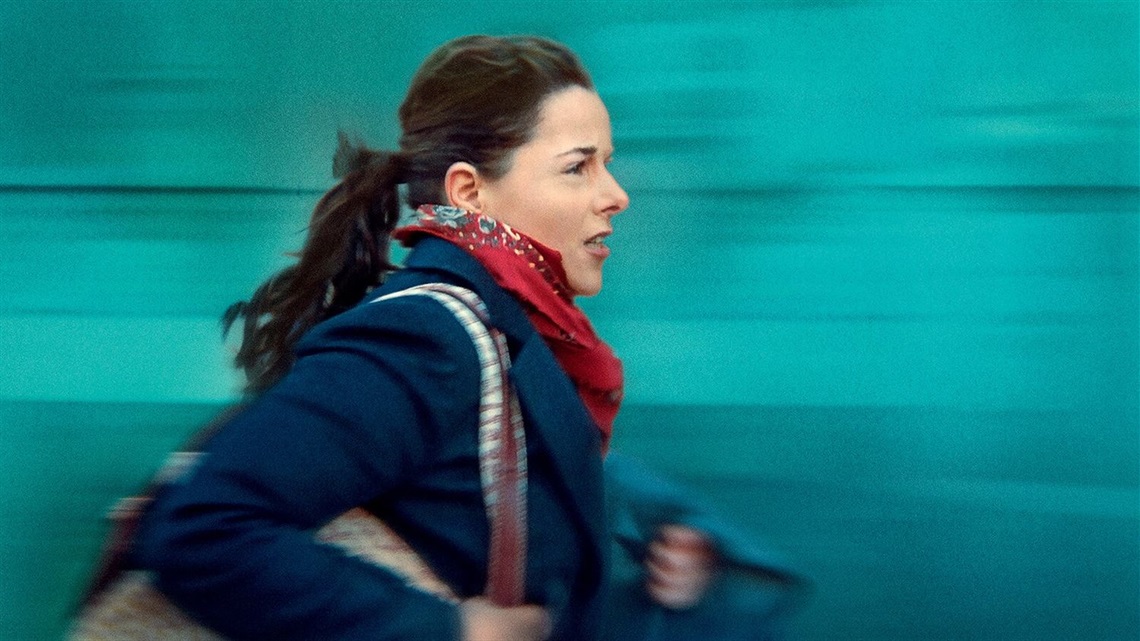 A woman with a frantic expression rushes past.