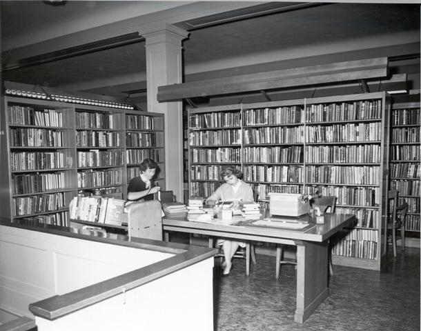 two women sitting at a table in the collection stacks of Grand library