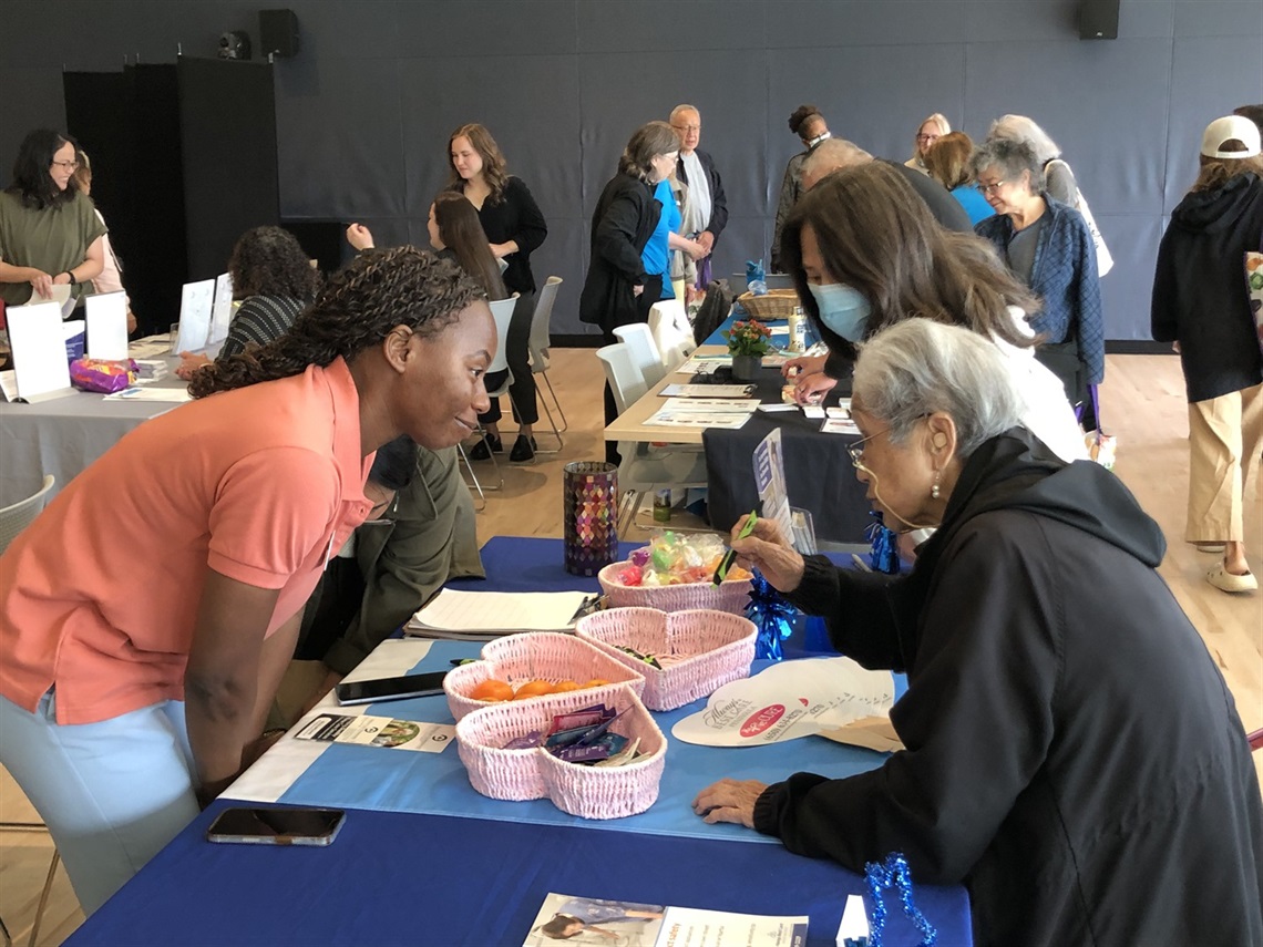 Photo of a Park and Recreation Senior Health Fair with older adults and staff engaging at information tables. Attendees receive resources, giveaways, and health information in an indoor community space.