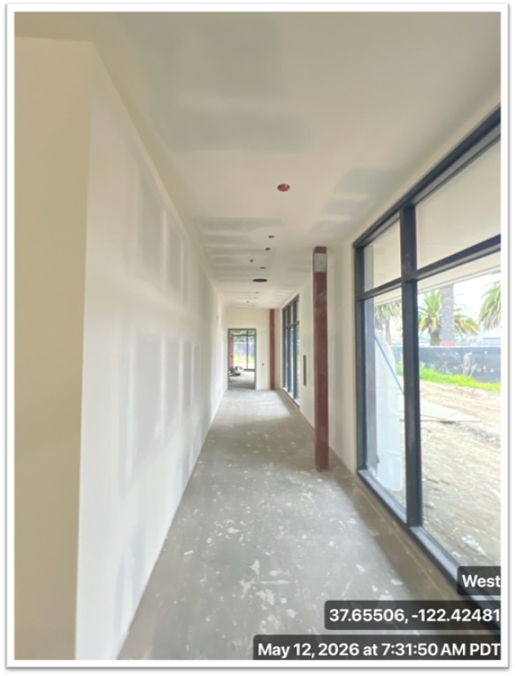 hallway with drywall on the left and glass wall on the right