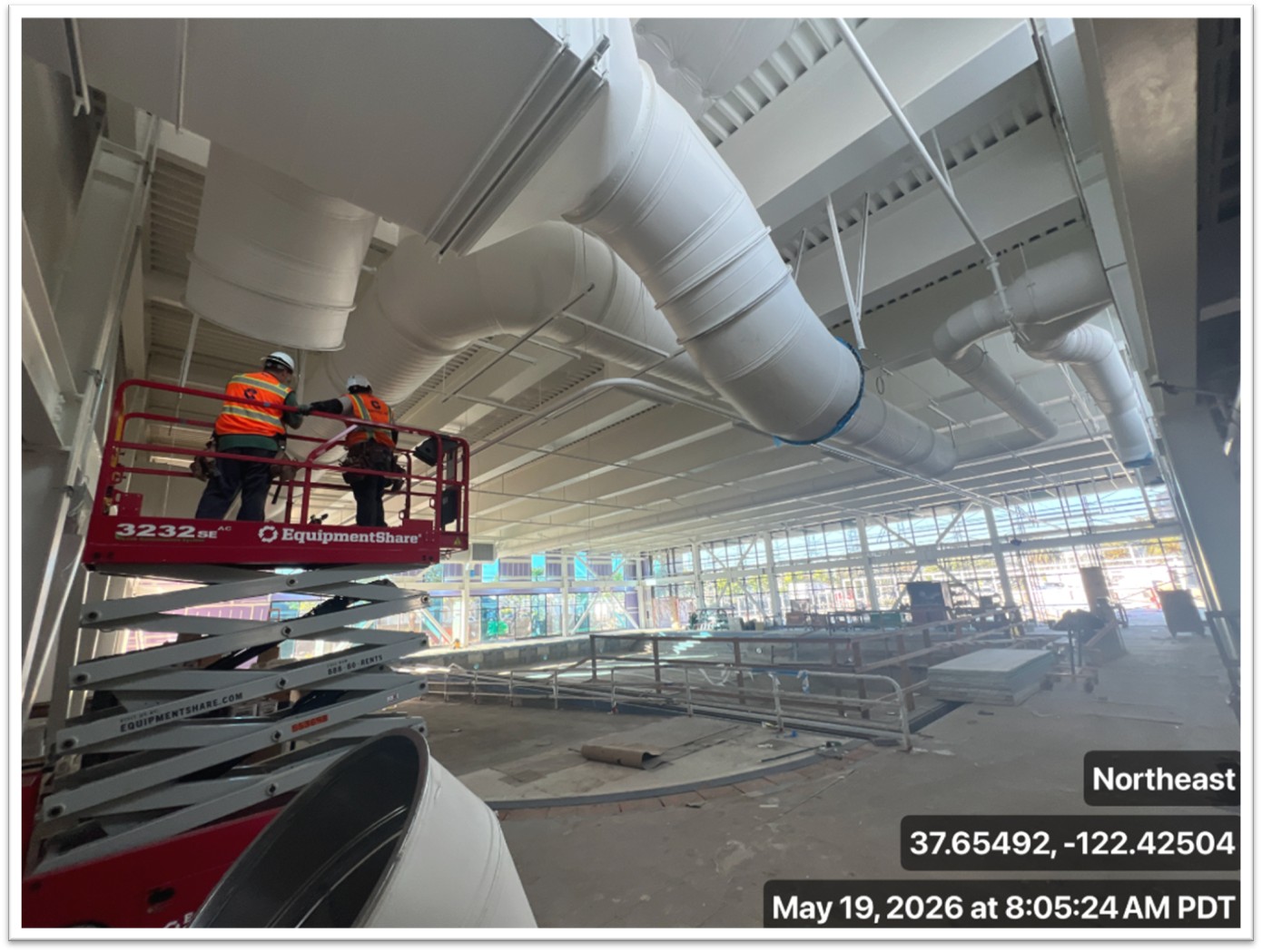 two construction workers on a scissor lift at indoor pool