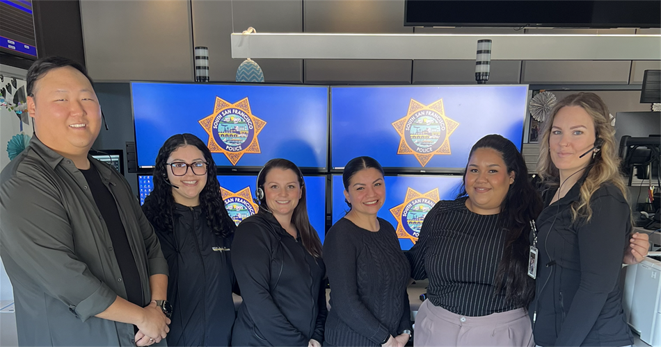 Dispatch team standing together in front of various monitors on the Communications floor