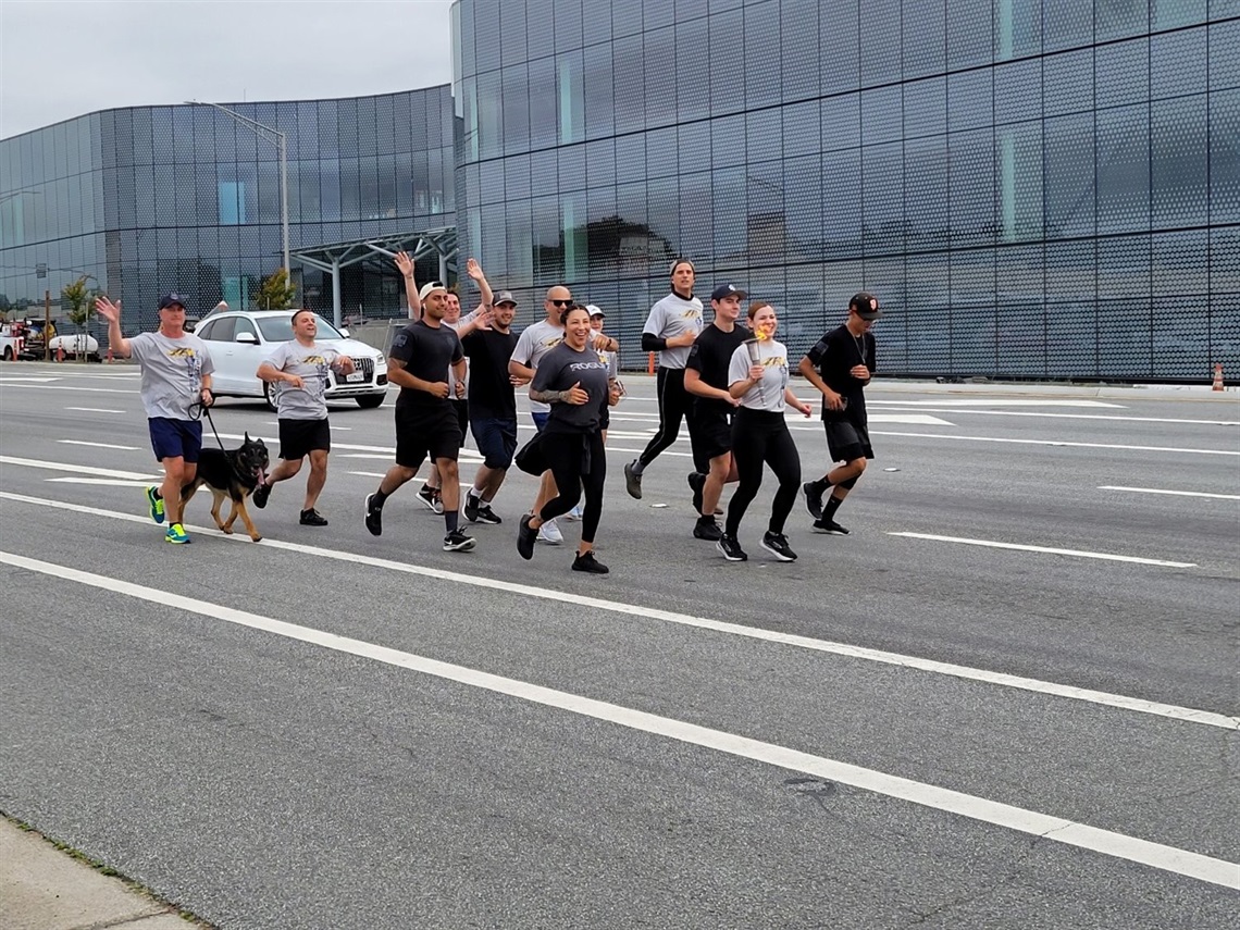 SSF Police Officers participating in the torch run; running on El Camino while wearing gray and black shirts