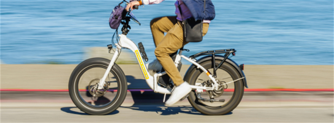 A person riding a white bicycle along the waterfront
