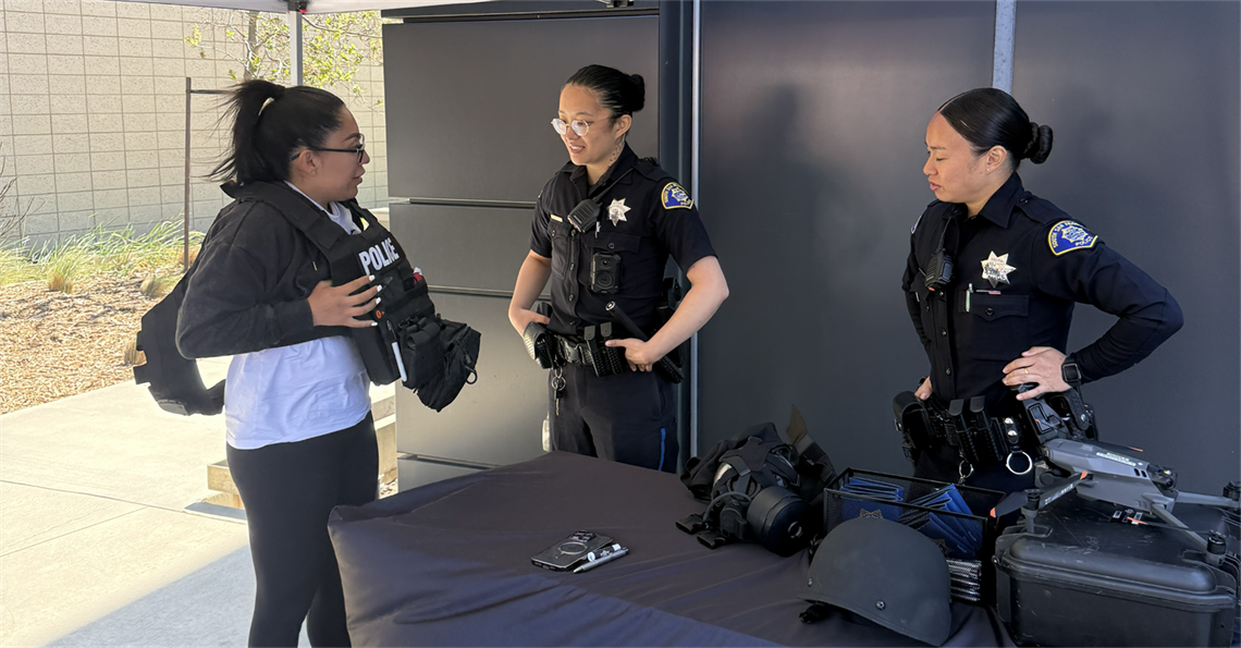 Workshop participant trying on Police equipment and talking to Police staff
