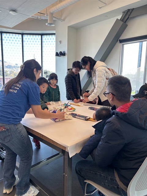 Youth and families participating in an activity around a table.